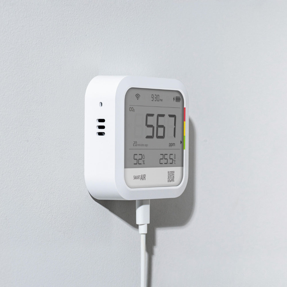 White air quality monitor with digital display on a gray background